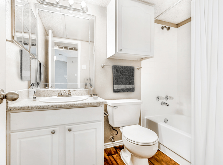 Virtually staged bathroom with granite inspired countertops, medicine cabinet, custom vanity mirrors, and white cabinetry with sheer shower curtain